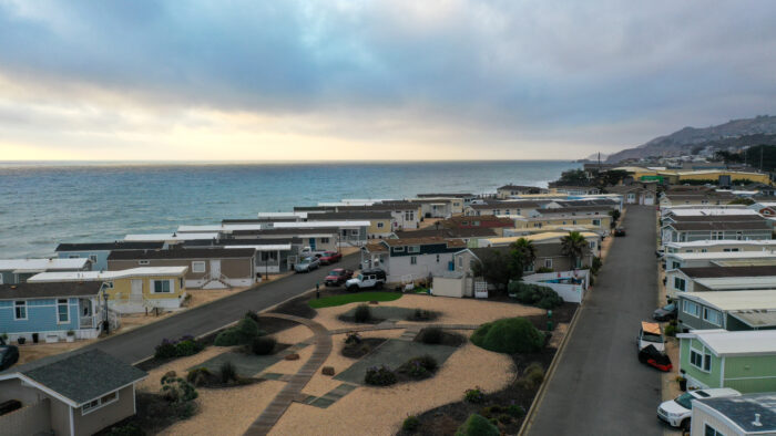 Aerial view of coastal mobile homes near the ocean, with a landscaped central area and overcast sky in Pacifica, CA