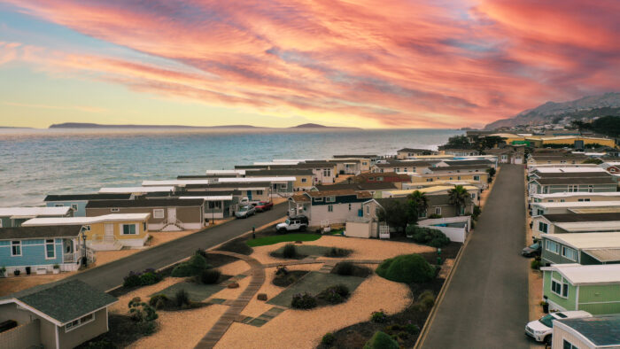 Community of mobile homes near the ocean, with landscaped common areas and a vivid sunset over the water in Pacifica, CA
