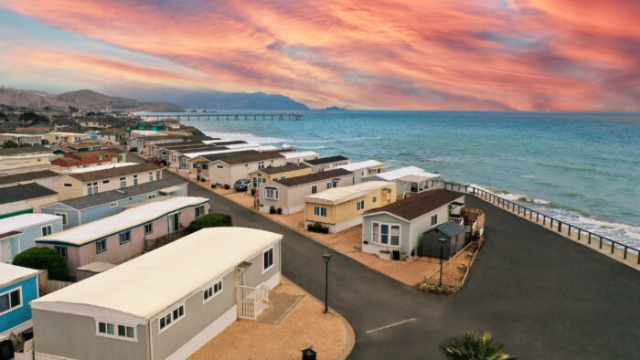 Aerial view of oceanfront mobile homes under a vivid sunset sky with a pier in the distance in Pacifica, CA